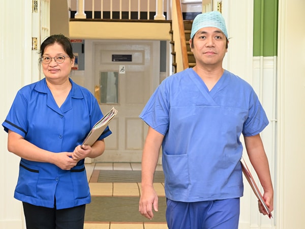 2 nurses in scrubs Eye and Ear hospital walking in the corridor and looking at camera